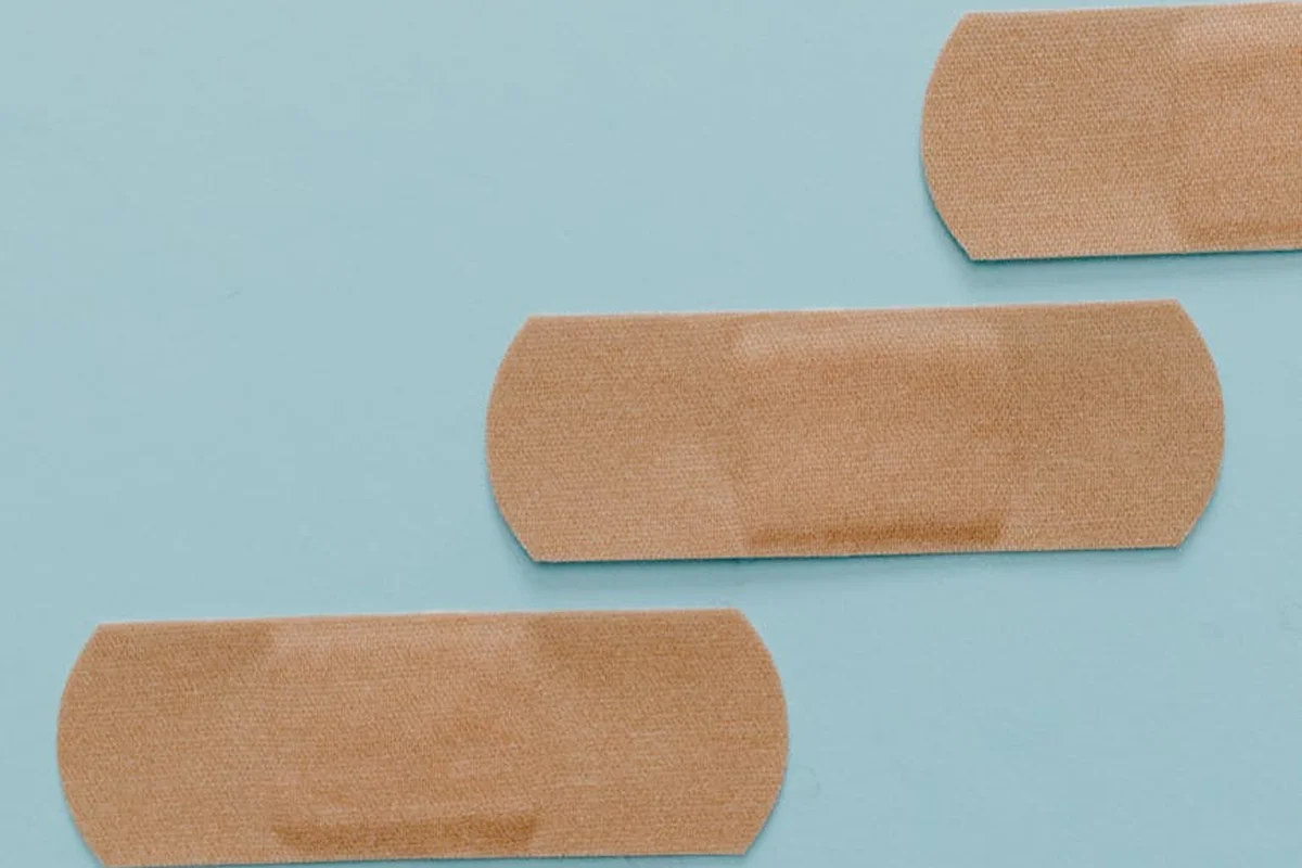 Three beige adhesive bandages on a light blue background