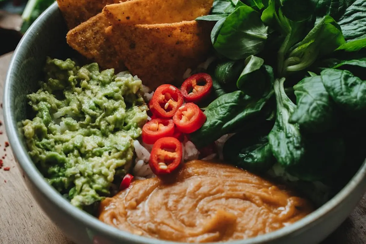 Bowl of leafy greens with sliced red peppers and a green puree, illustrating a greens medley for a bearded dragon