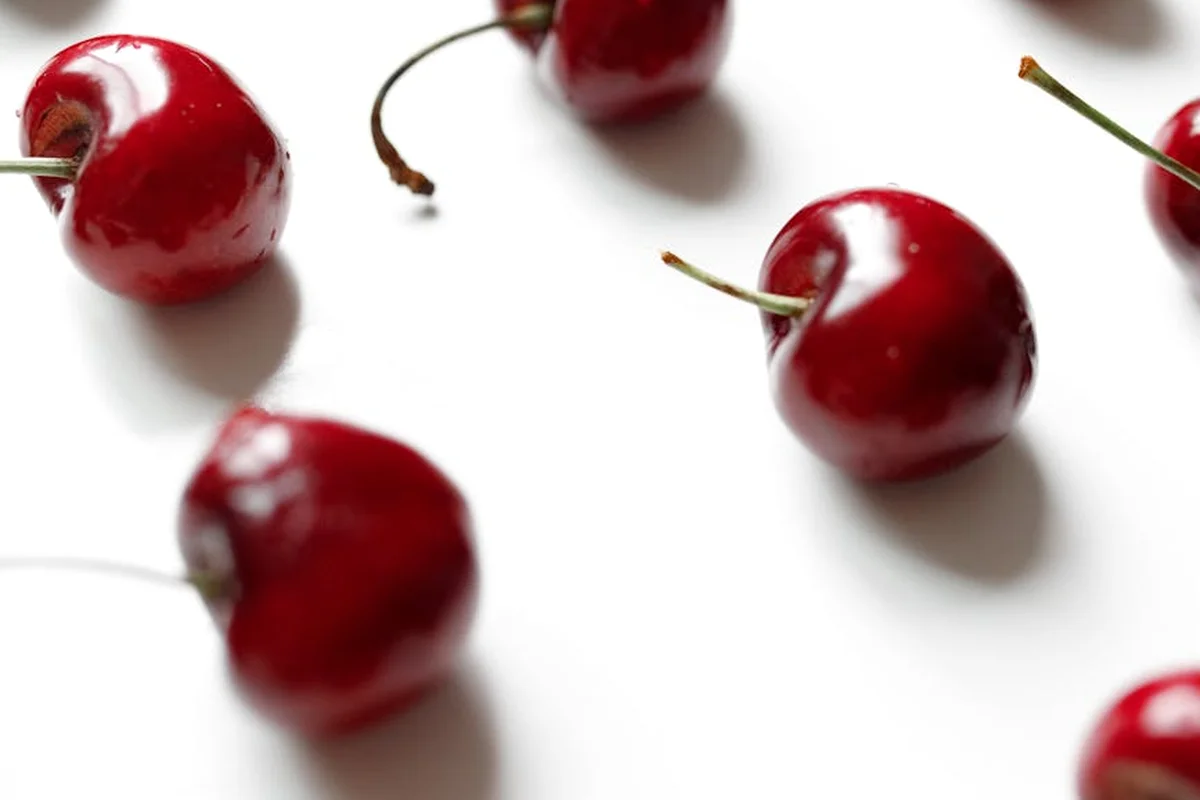 Bright red cherries scattered on a white background