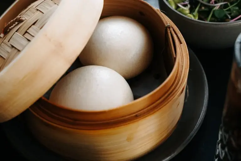 Two white eggs in a round bamboo steamer.