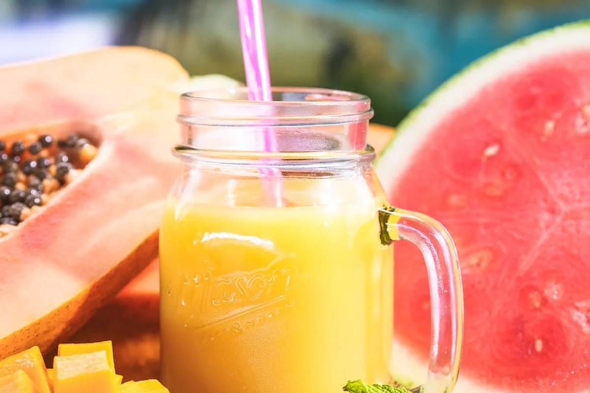Sliced papaya and watermelon with a jar of juice in the foreground, illustrating safe fruit options for bearded dragons.