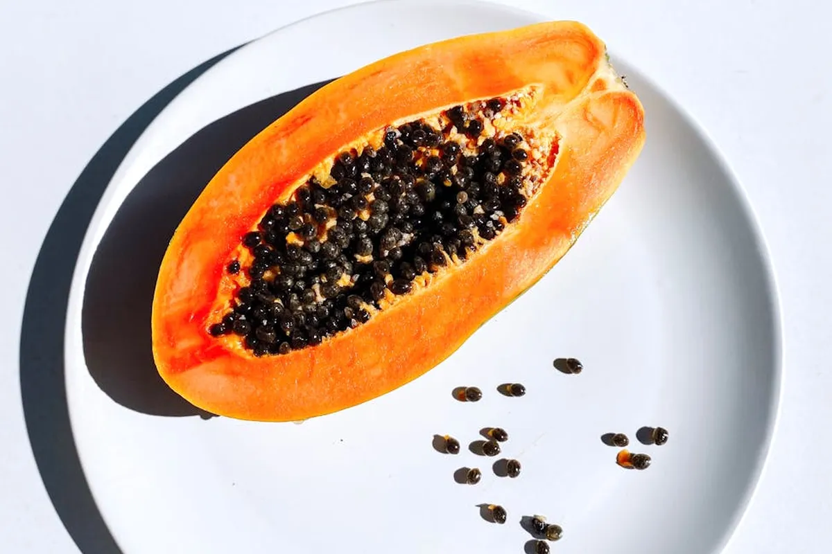 Halved papaya with black seeds on a white plate