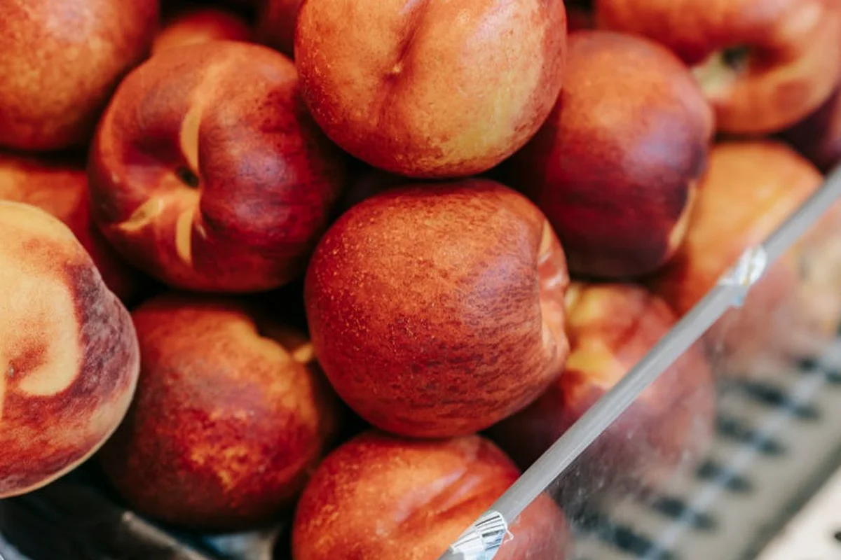 Close-up of ripe peaches in a container with a clear plastic lid