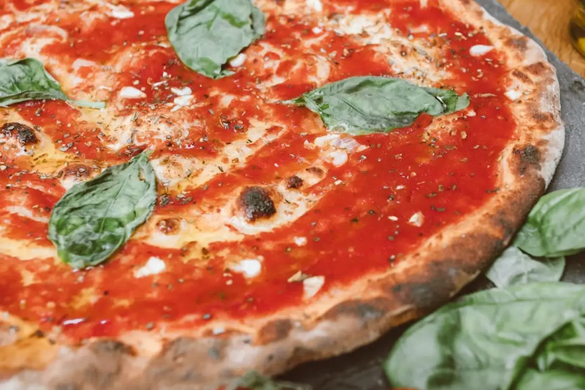 Close-up of a pizza topped with tomato sauce, melted cheese, and fresh basil leaves.
