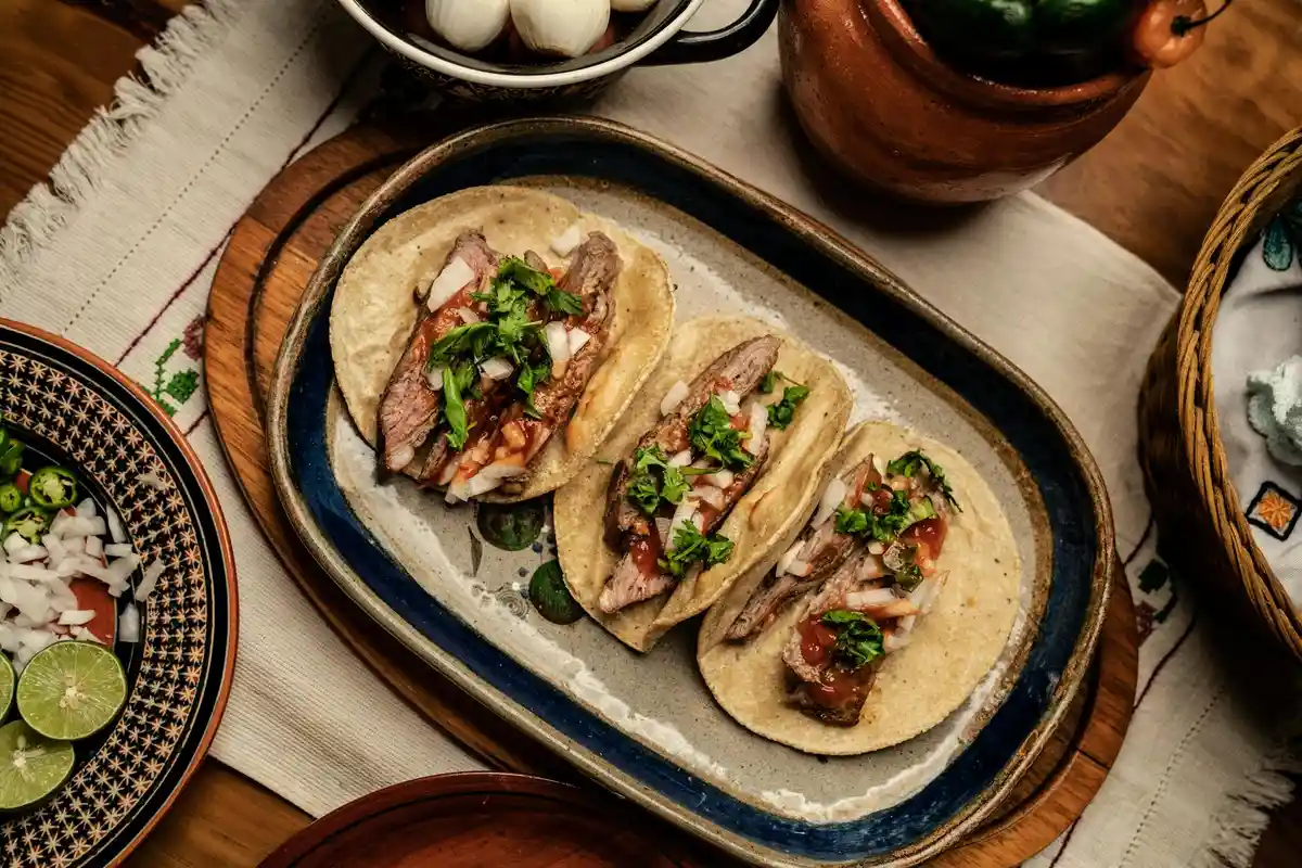 Plate of tacos topped with fresh cilantro garnish on a wooden table