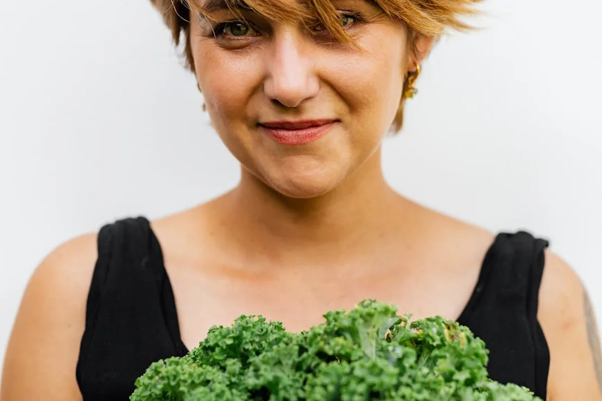 Smiling person holding a bunch of fresh kale
