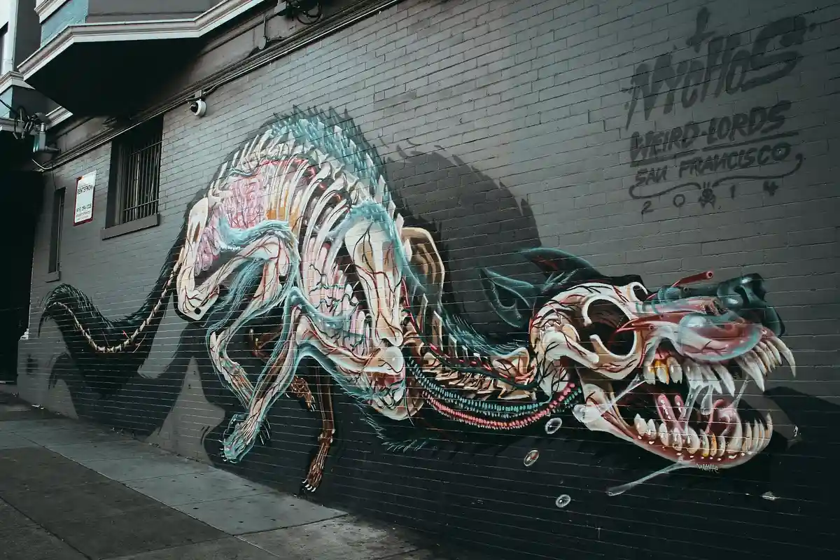 Colorful graffiti mural of a dragon painted on a brick wall in an urban alley.